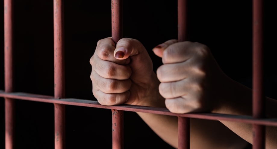 Female hands holding prison bars