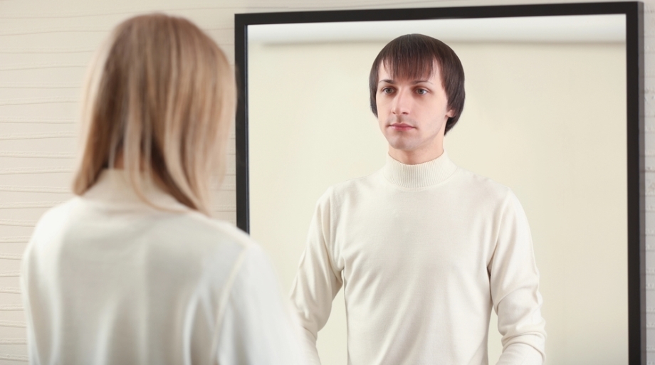 Woman looking in mirror - transgender concept