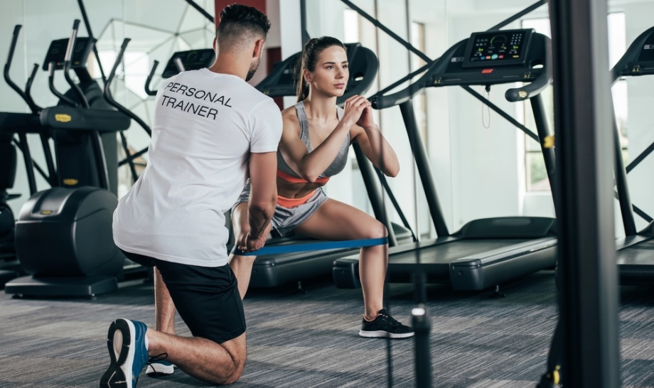 Personal trainer supporting female fitness student