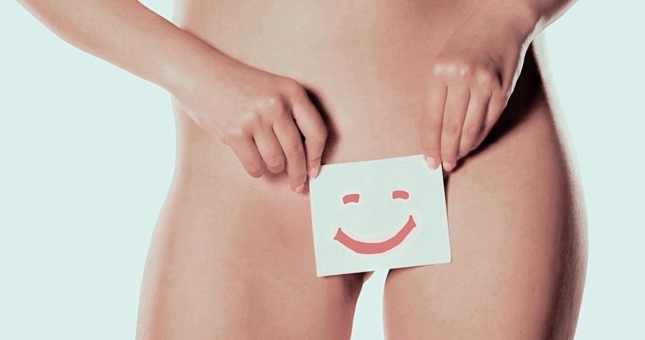 Unclothed woman with smiling card in front of intimate parts