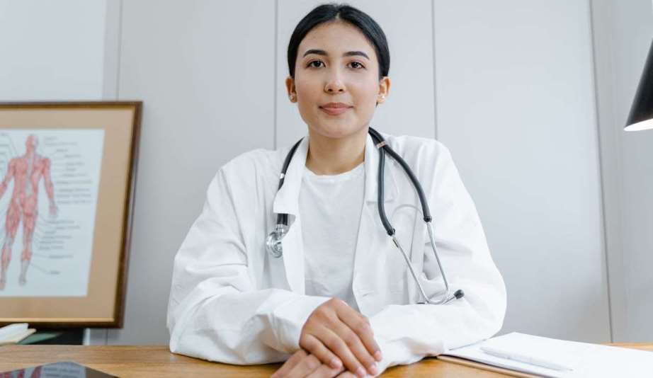 Woman in white scrub suit wearing black stethoscope