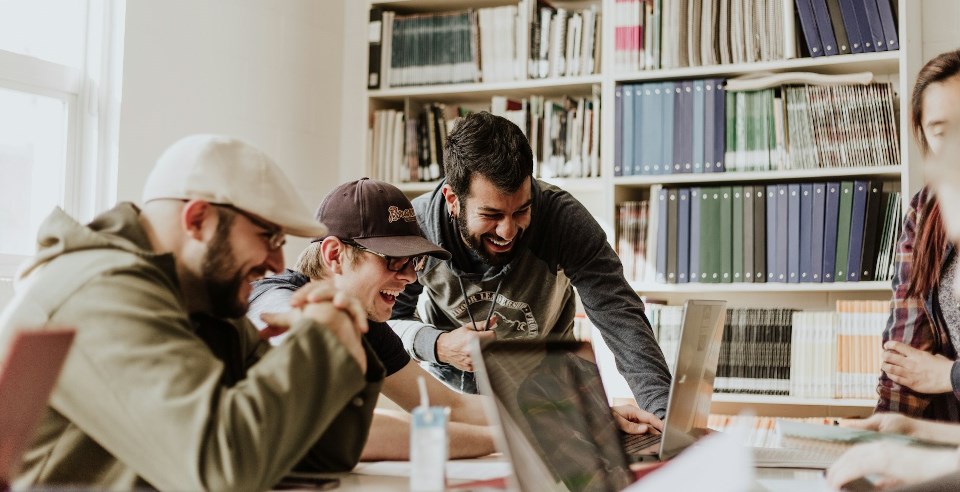 Three men in business room behind laptop